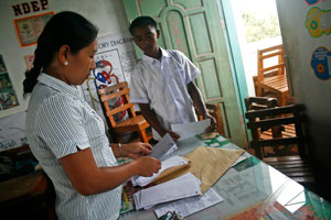 Margie Jimena, 31, a Grade 6 teacher at the Marahan West Elementary School in Marilog District, Davao City checks a report card before giving it to a former pupil who is now in high school. Jimena has been teaching for seven years and hopes to hitchhike as often as possible to save on transportation expenses, which cost P100 round trip. MindaNews Photo by Ruby Thursday More