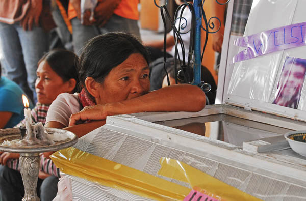 MOTHER IN GRIEF. Rosita Gica sits beside the coffin bearing his son, Welcie,  who was killed on August 24 by security guards of a ranch owner in Maramag town, Bukidnon.  Rosita and the farmers belonging to the Panalsalan Dagumbaan Tribal Association (Padata), brought the remains of Welcie to the regional office of the National Commission on Indigenous People in Cagayan de Oro City on Thursday, Sept 1.. MindaNews photo by Froilan Gallardo