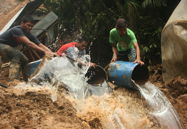 Concerned miners help in retrieval operations by flushing barrels of water to remove dirt at a landslide that hit Barangay Napnapan, Pantukan in Compostela Valley morning of January 5 killing at least 36 people. MindaNews Photo by Toto Lozano