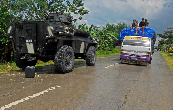 SAFE PASSAGE. A cargo truck passes by an Army Simba Armored Personnel Carrier (APC) parked on the highway in Datu Unsay town in Maguindanao on August 11, 2012. The Army has opened to motorists the vital highway linking Cotabato and Isulan cities after they recaptured rebel strongholds in Datu Unsay town. MindaNews photo by Froilan Gallardo