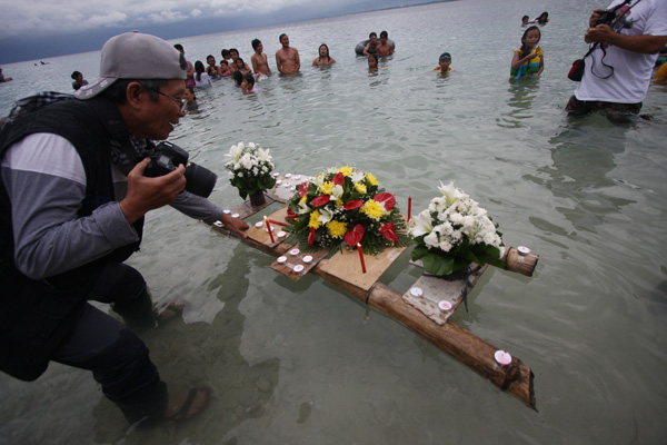 FLOWERS FOR GENE BOYD. Photjournalist Rene Lumawag leads a group of photo enthusiasts on Sunday during the candle lighting and offering of flowers at the public beach in Punta Dumalag, Davao City, in commemoration of the 8th death anniversary of his son Gene Boyd. Gene Boyd, MIndaNews photo editor, was gunned down in Jolo, Sulu on Nov. 12, 2004, after shooting the sunset at the Jolo pier About 60 photographers came supposedly for a sunset shoot but the skies were overcast. Mindanews photo by Ruby Thursday More