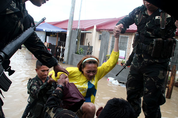 RESCUED. Elements of Philippine Army's Bravo Company of the 69th Infantry Battalion evacuate residents of Deca Homes in Barangay Tigatto, Davao City on Sunday as water level in Davao River rose due to heavy rains. Mindanews Photo by Keith Bacongco
