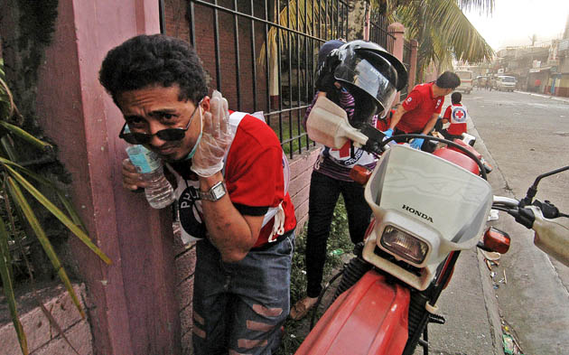 Red Cross personnel helping treat victims in Zamboanga City seek cover after an M203 grenade fired by rebels landed in front of their team on Friday, September 13, 2013. MindaNews photo by Froilan Gallardo