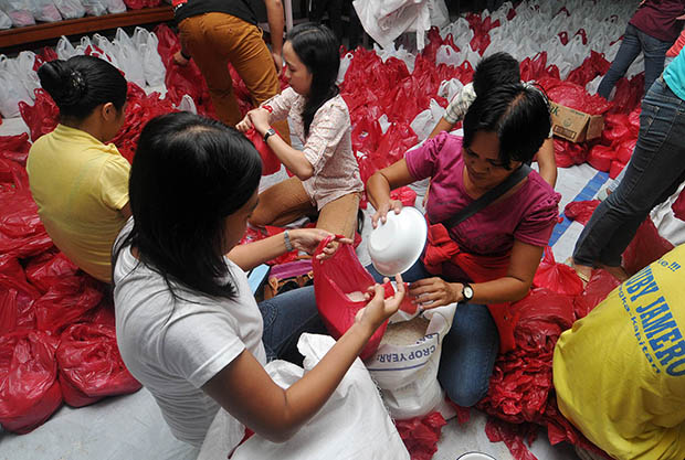 Volunteers pour rice into relief bags—two kilos per bag—at Mt. Carmel Church in Barangay Carmen, Cagayan de Oro City on Nov. 12. Hundreds of people including Sendong victims responded to calls by the Department of Social Welfare and Development to help repack 50,000 relief bags a day for the victims of Typhoon Yolanda. MindaNews photo by Froilan Gallardo