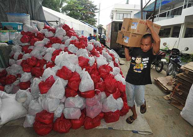 A volunteer carries boxes of sardines at the repacking center of the regional office of the Department of Social Welfare Development in Masterson Avenue in Cagayan de Oro City on Nov. 12. Hundreds of people including Sendong victims responded to calls by the Department of Social Welfare and Development to help repack 50,000 relief bags a day for the victims of Typhoon Yolanda. MindaNews photo by Froilan Gallardo