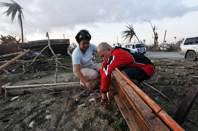 Ferdinand Lomuntag and his wife Donna light a candle on a small vacant lot along an intersection at the Maharlika Highway in Barangay Calogcog in Tanauan town, Leyte on 24 Nov 2013. The lot is a mass grave containing 50 Typhoon Yolanda victims, including Donna’s mother, 12 nephews and nieces, 2 in-laws and a grandchild. MindaNews photo by Froilan Gallardo