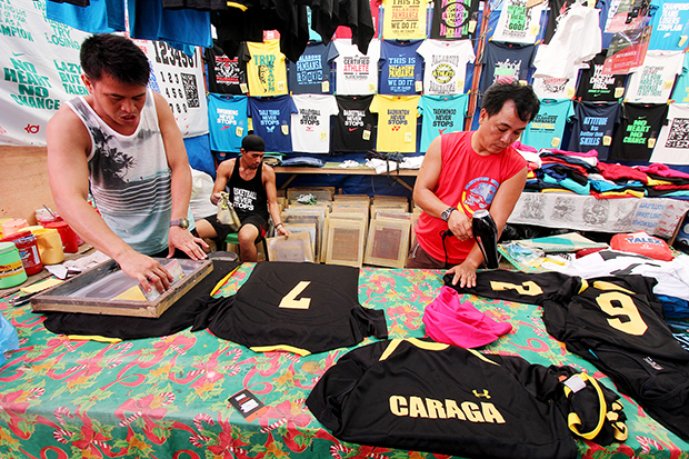 LUCRATIVE BUSINESS. Vendors print numbers on the jersey of Caraga football players on Wednesday, Ma6. These vendors came all the way from Manila to run a shirt prining business in the ongoing Palarong Pambansa in Tagum City, Davao del Norte. Mindanews Photo by Keith Bacongco
