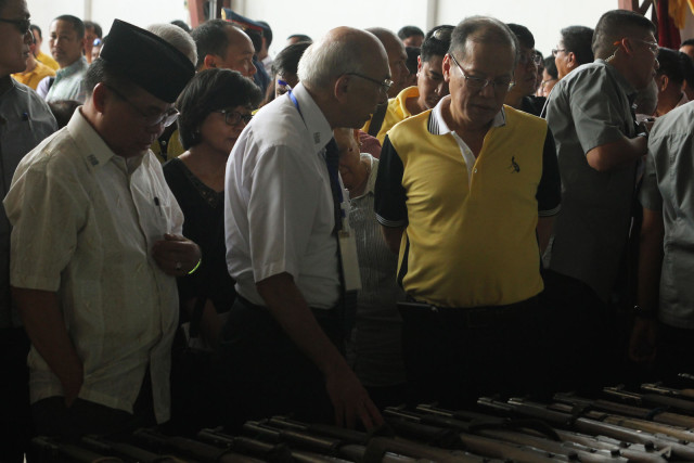 Moro Islamic Liberation Front chair Al Hadj Murad Ebrahim and President Benigno Aquino III inspect the firearms during a ceremonial turnover at the old Maguindanao provincial capitol in Sultan Kudarat on June 16, 2015. The MILF turned over a total of 75 weapons as an initial step toward decommissioning. MindaNews photo by Toto Lozano