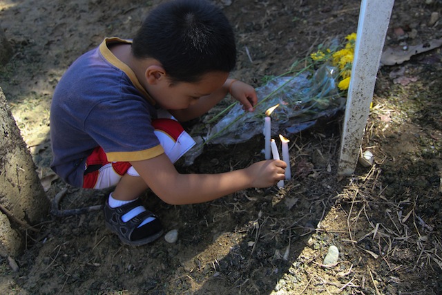 FIRST TIME. Five-year old Ronnie “Nono” Perante III offers candles at the symbolic gravemarker of his father Ronnie Perante at the site of the November 23, 2009 massacre of in Sitio Masalay, Barangay Salman, Ampatuan, Maguindanao on Saturday, November 20, 2015. It was Nono’s first visit to the massacre site. Nono was still in his mother’s womb when his father, a reporter of Gold Star Daily, was killed along with 57 others in the worst pre-election violence in Philippine history. MindaNews photo by TOTO LOZANO