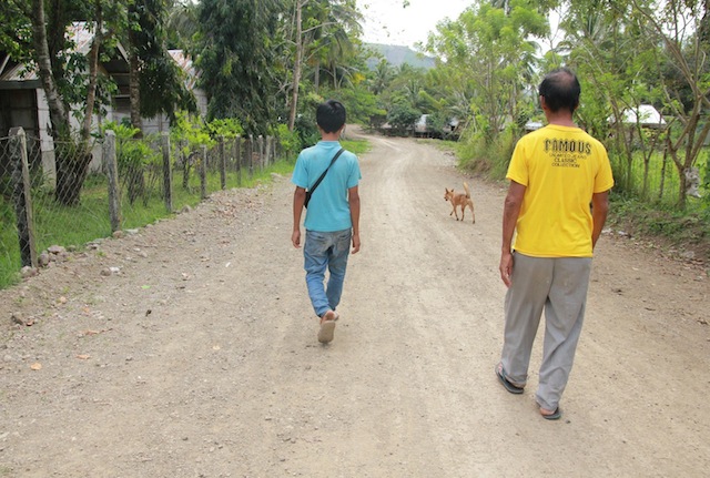 HOME. Orlando “Kaido” Engo, 52, and 15-year old son Jerome on their way home in Sitio Matamis, Barangay Demoloc on March 11. Kaido said he will file charges against the Army corporal and four SCAA members. MindaNews photo by TOTO LOZANO 