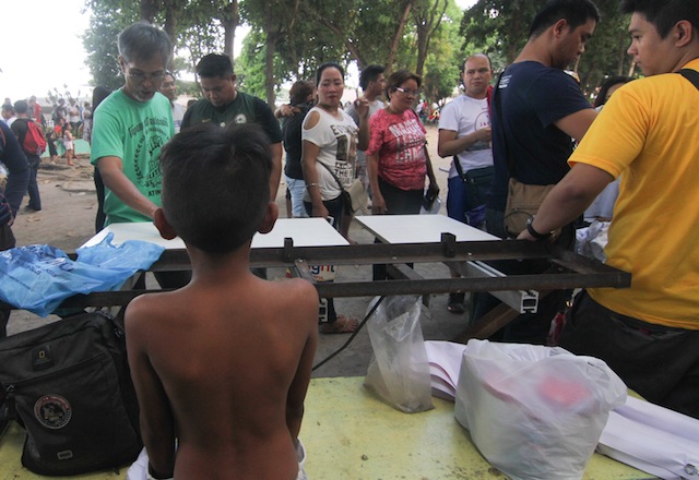 FIRST IN LINE. A young boy removes his shirt as he waits for a team of graphic artists set up their booth for a free t-shirt printing session for supporters of Davao City mayor and presidential candidate Rodrigo Duterte at Rizal Park, Koronadal City on April 9, 2016. MindaNews photo by TOTO LOZANO